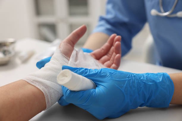 doctor bandaging patient's burned hand in hospital, closeup doctor bandaging patient's burned hand in hospital, closeup