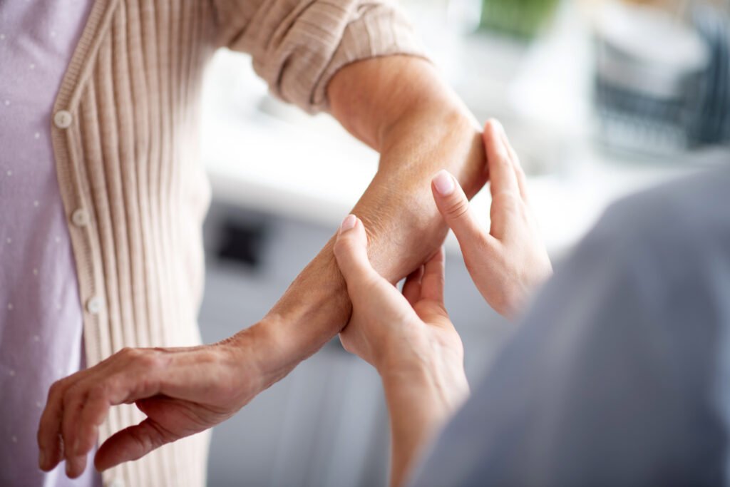 helpful nurse putting cream on elbow for retired woman